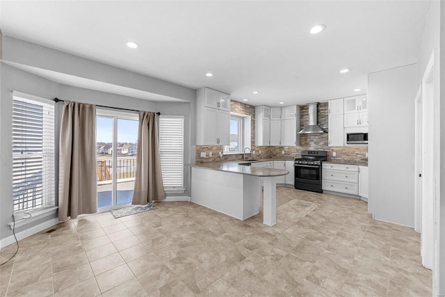 kitchen with white cabinets, a peninsula, wall chimney range hood, stainless steel range with gas cooktop, and a sink