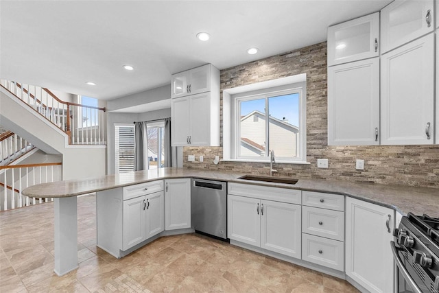 kitchen featuring white cabinets, range with gas cooktop, a peninsula, stainless steel dishwasher, and a sink