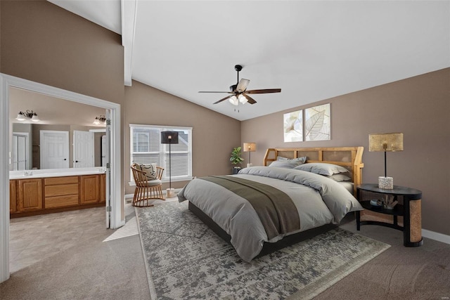 bedroom with lofted ceiling, ensuite bathroom, light colored carpet, a ceiling fan, and baseboards