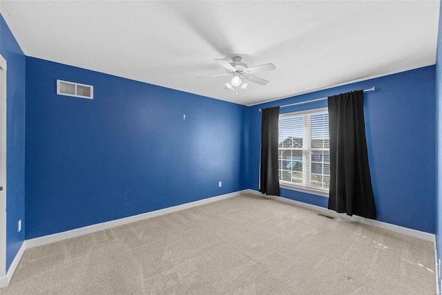 carpeted spare room with ceiling fan, visible vents, and baseboards