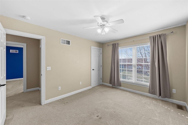 carpeted spare room with ceiling fan, visible vents, and baseboards