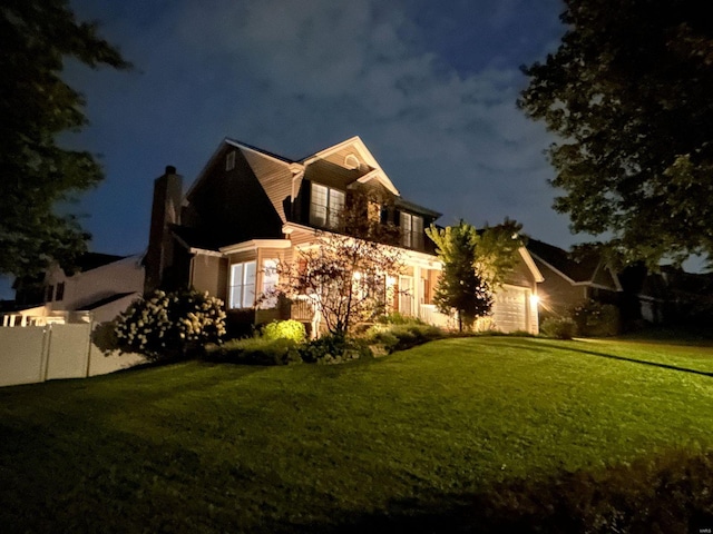 property exterior at twilight featuring an attached garage, a chimney, and a yard