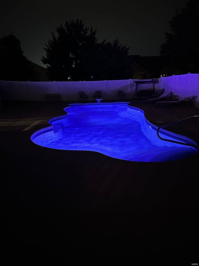 pool at twilight with a fenced backyard and a fenced in pool