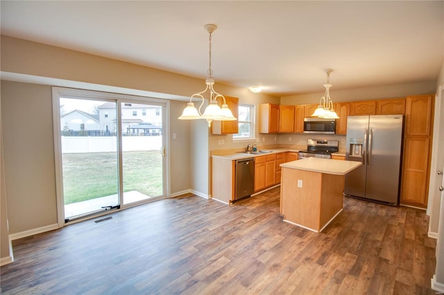 kitchen with stainless steel appliances, a center island, dark wood-type flooring, and decorative light fixtures