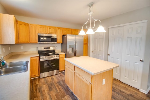 kitchen with sink, appliances with stainless steel finishes, hanging light fixtures, a kitchen island, and dark hardwood / wood-style flooring