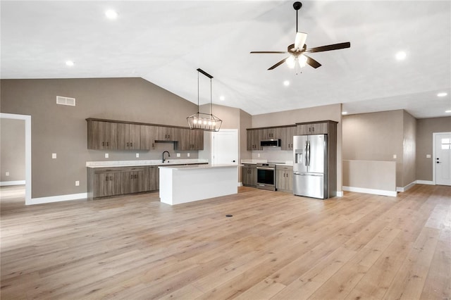 kitchen with appliances with stainless steel finishes, hanging light fixtures, a center island, ceiling fan, and light wood-type flooring