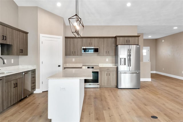 kitchen featuring sink, hanging light fixtures, a center island, stainless steel appliances, and light hardwood / wood-style flooring