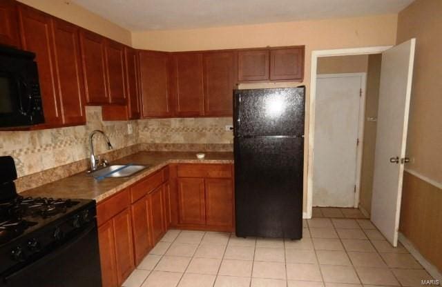 kitchen with tasteful backsplash, sink, light tile patterned floors, and black appliances