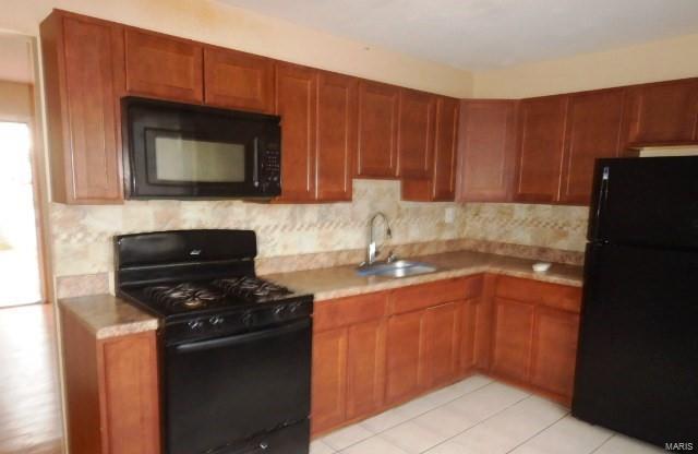 kitchen featuring sink, decorative backsplash, black appliances, and light tile patterned flooring