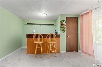 kitchen featuring a breakfast bar, light carpet, and a textured ceiling