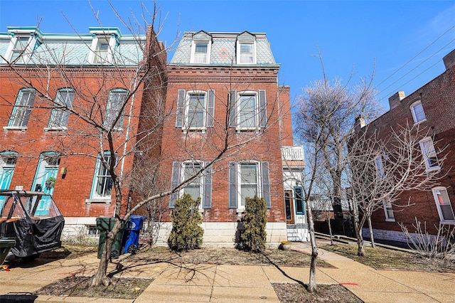 view of front of house with entry steps, brick siding, a high end roof, and mansard roof