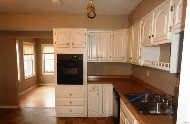 kitchen featuring sink, black appliances, and white cabinets