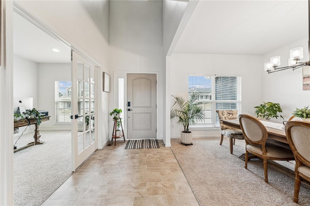 foyer entrance featuring a chandelier, a wealth of natural light, and light colored carpet