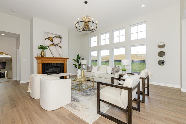 living area with a chandelier, a tile fireplace, baseboards, and light wood finished floors