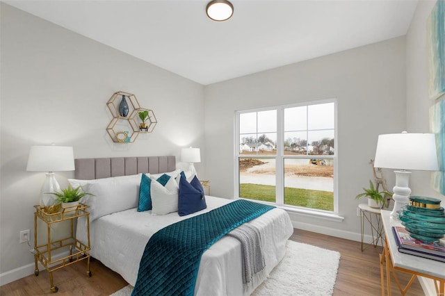 bedroom featuring multiple windows, light wood-style flooring, and baseboards