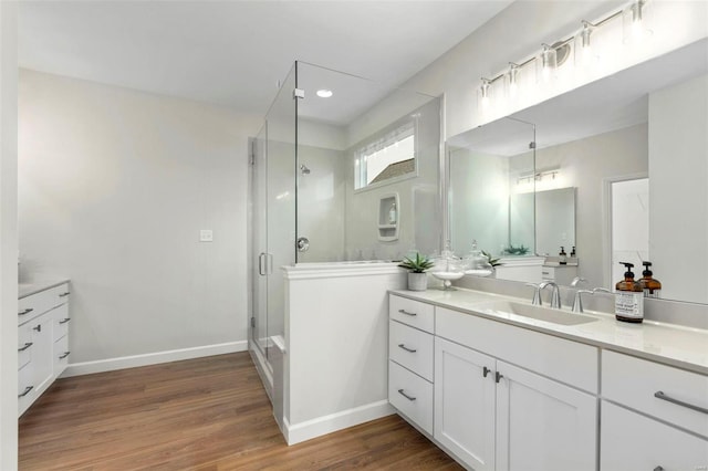 bathroom featuring a stall shower, vanity, baseboards, and wood finished floors