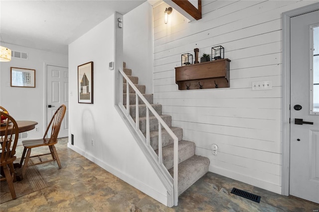 staircase featuring wooden walls and visible vents