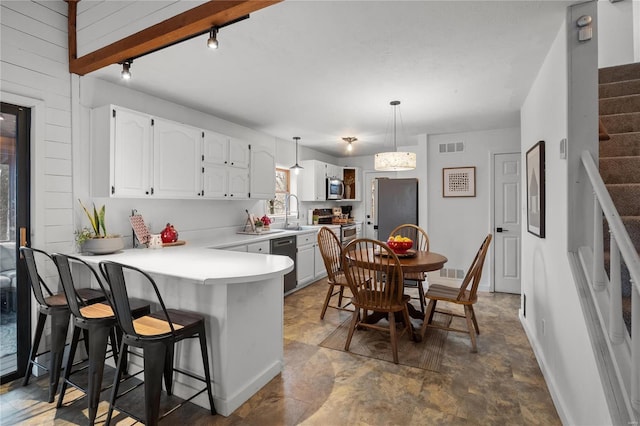 kitchen with a breakfast bar, visible vents, appliances with stainless steel finishes, white cabinetry, and a peninsula