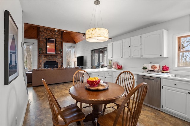 dining room with lofted ceiling and a stone fireplace