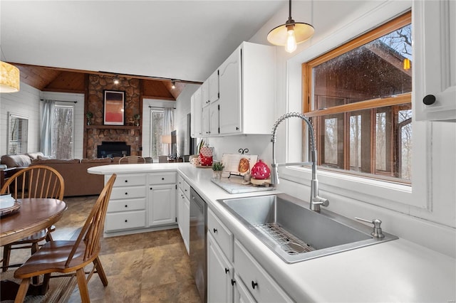 kitchen featuring lofted ceiling, white cabinets, dishwasher, and a sink