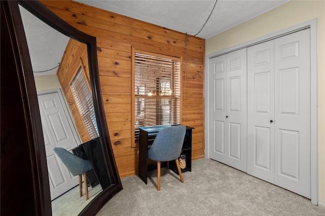 home office with light carpet, wooden walls, and a textured ceiling