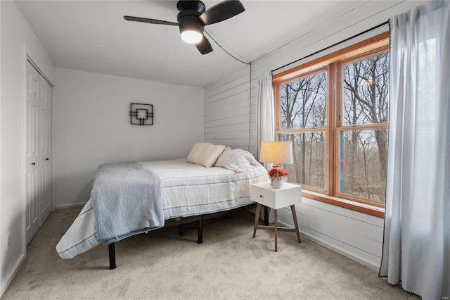 bedroom featuring wood walls, carpet, a closet, and a ceiling fan