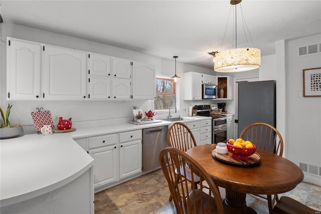 kitchen featuring appliances with stainless steel finishes, a sink, visible vents, and white cabinets