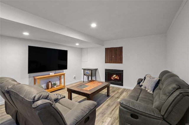 living room with baseboards, a lit fireplace, recessed lighting, and light wood-style floors