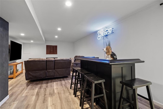 bar with a bar, wood finished floors, and recessed lighting