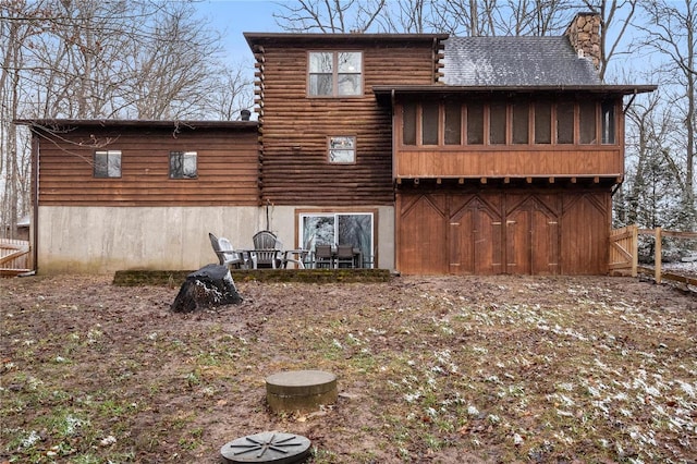 back of house featuring log exterior, a chimney, and fence