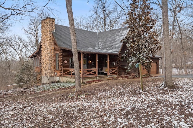 log cabin featuring a porch, a chimney, roof with shingles, and log exterior