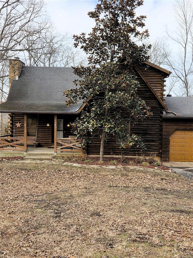 cabin featuring a garage, covered porch, and log exterior