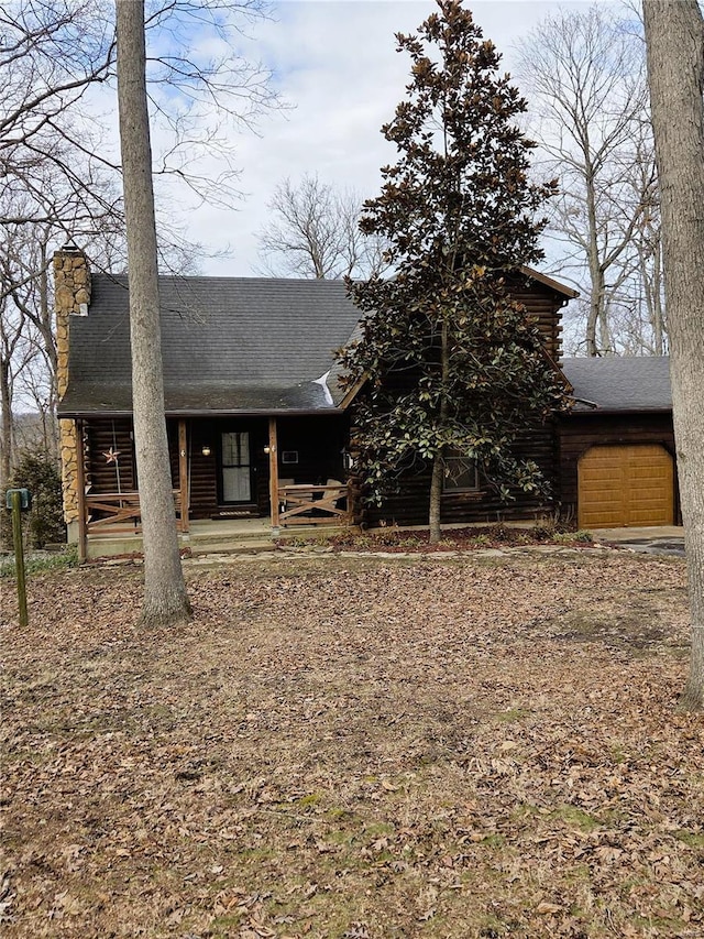 view of front of house featuring covered porch, an attached garage, and log siding