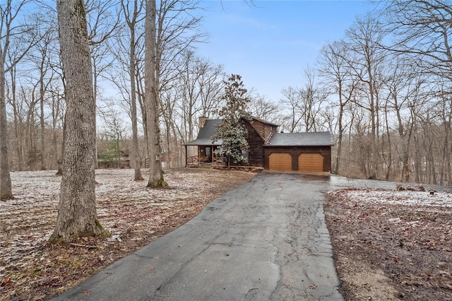 view of front facade with driveway, an attached garage, and a chimney