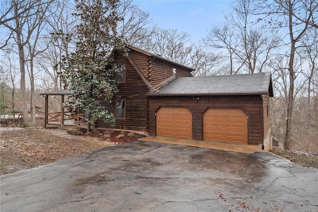 view of side of home with an attached garage, driveway, and log siding