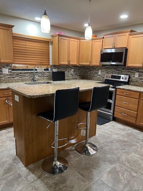 kitchen featuring a kitchen breakfast bar, decorative light fixtures, light stone countertops, stainless steel appliances, and a sink