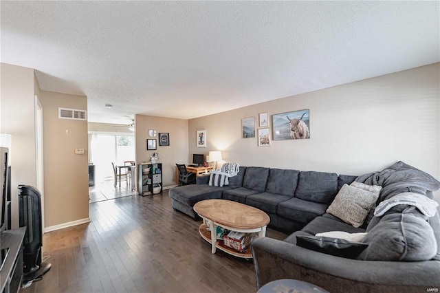 living room featuring dark hardwood / wood-style flooring, ceiling fan, and a textured ceiling