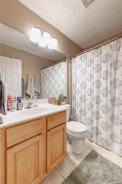 bathroom with tile patterned flooring, vanity, a textured ceiling, and toilet