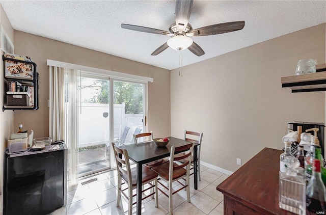 tiled dining area featuring ceiling fan and a textured ceiling