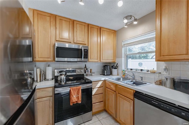 kitchen with tasteful backsplash, sink, light tile patterned floors, stainless steel appliances, and a textured ceiling