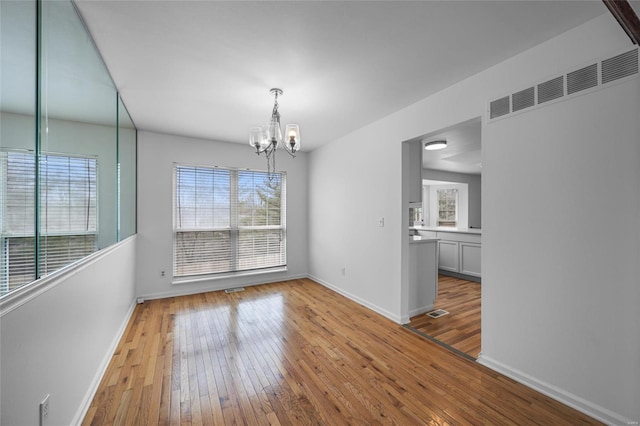 unfurnished dining area featuring a notable chandelier and light hardwood / wood-style flooring