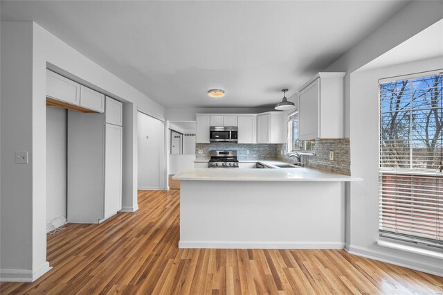 kitchen featuring sink, white cabinetry, backsplash, stainless steel appliances, and kitchen peninsula