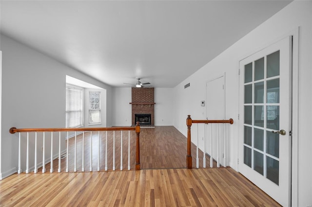 unfurnished living room featuring a brick fireplace, hardwood / wood-style floors, and ceiling fan