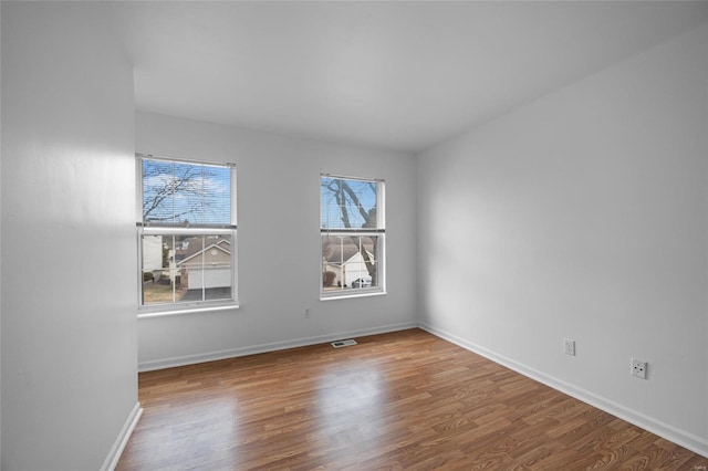 spare room with plenty of natural light and hardwood / wood-style floors