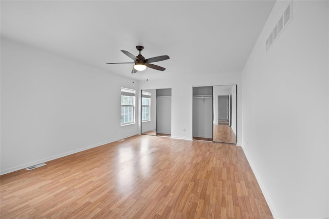 unfurnished bedroom with multiple closets, ceiling fan, and light hardwood / wood-style flooring