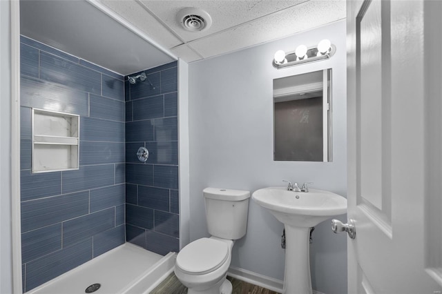 bathroom featuring sink, a tile shower, and toilet