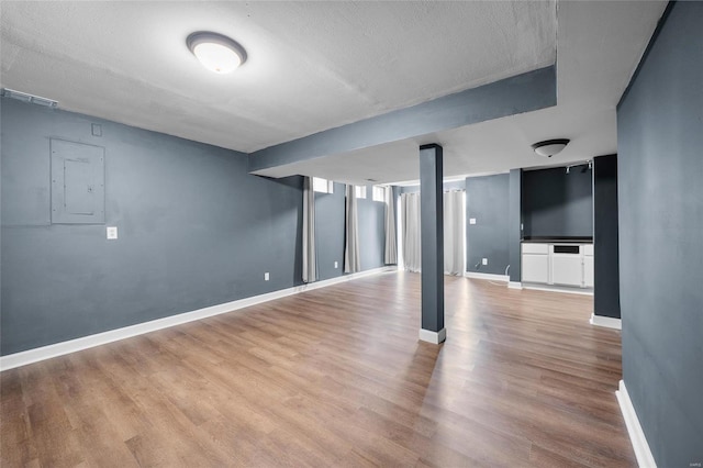 basement with hardwood / wood-style flooring, electric panel, and a textured ceiling