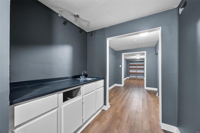 kitchen with white cabinetry, sink, and light hardwood / wood-style floors