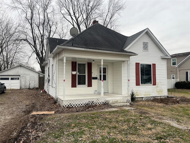 bungalow with a porch, a garage, and an outdoor structure