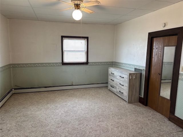 empty room with light carpet, ceiling fan, a paneled ceiling, and a baseboard radiator